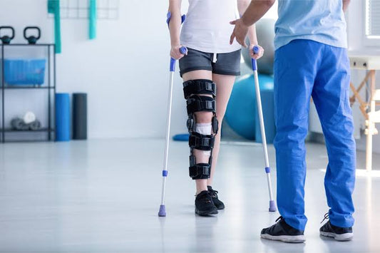 Patient using crutches with knee brace during physiotherapy session with medical support
